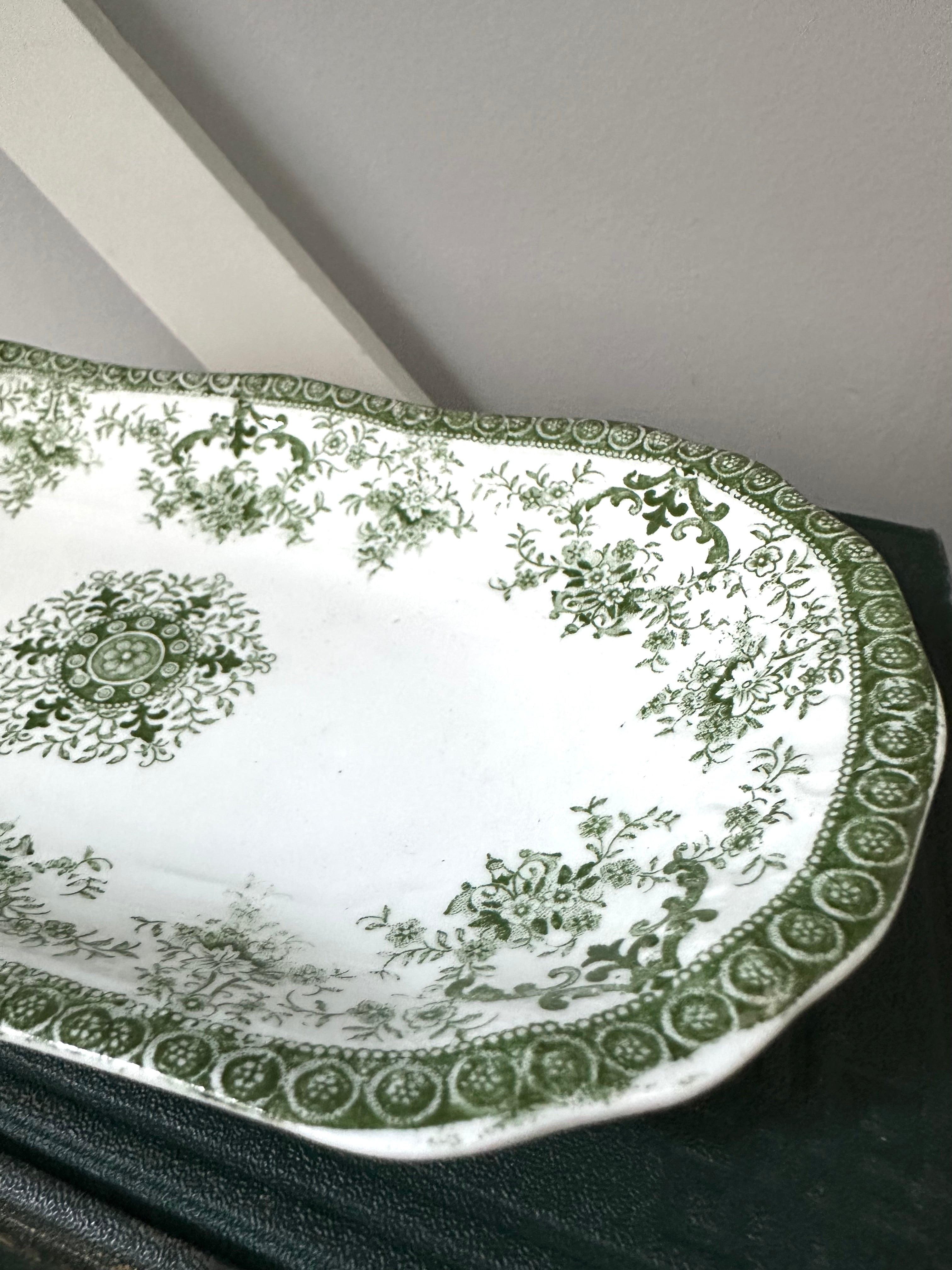 Decorative green and white plate with intricate patterns on a dark surface.