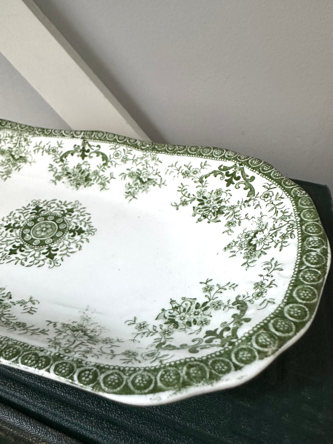 Decorative green and white plate with intricate patterns on a dark surface.