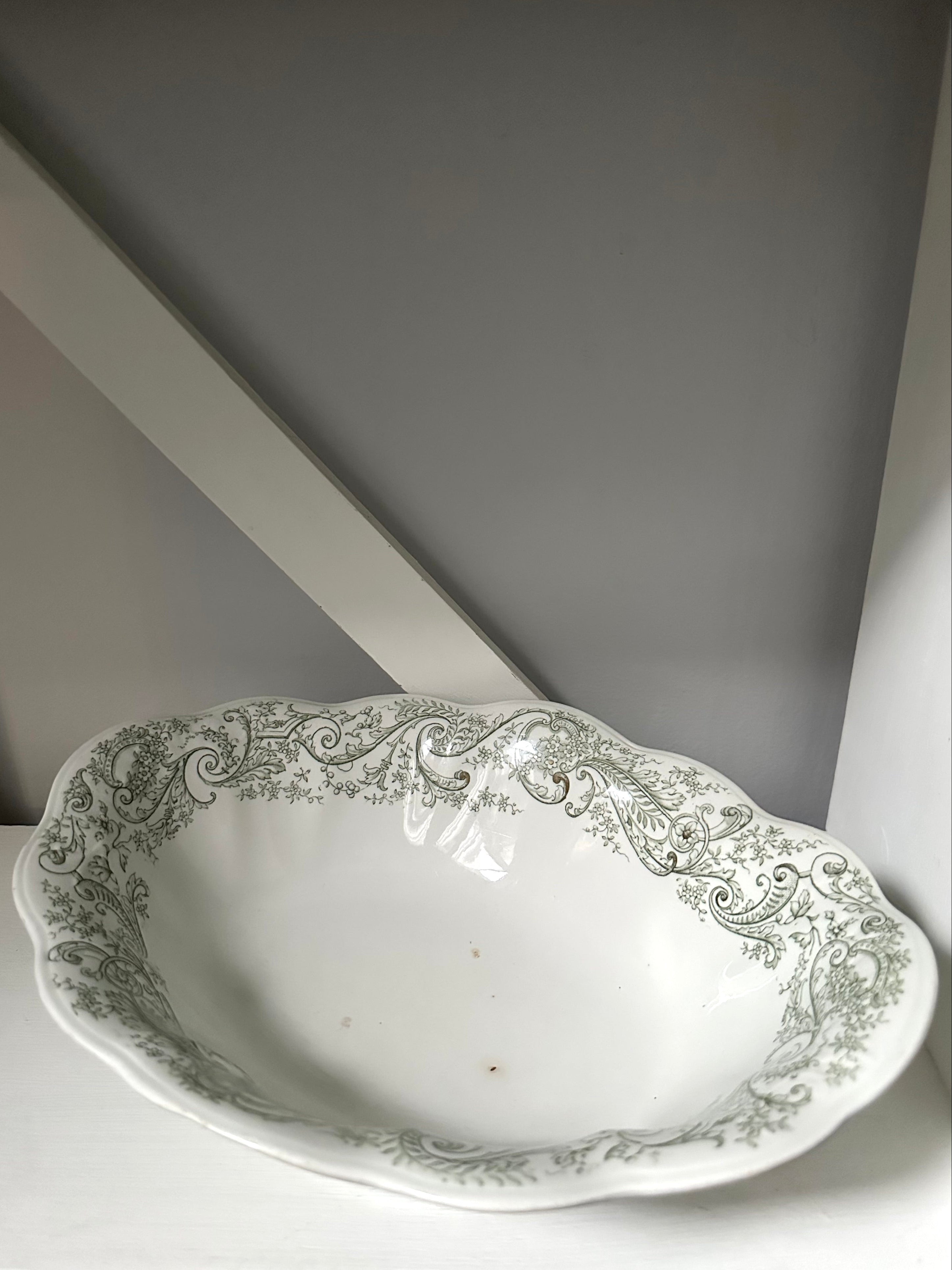 Decorative white ceramic bowl with intricate green patterns on a light gray background