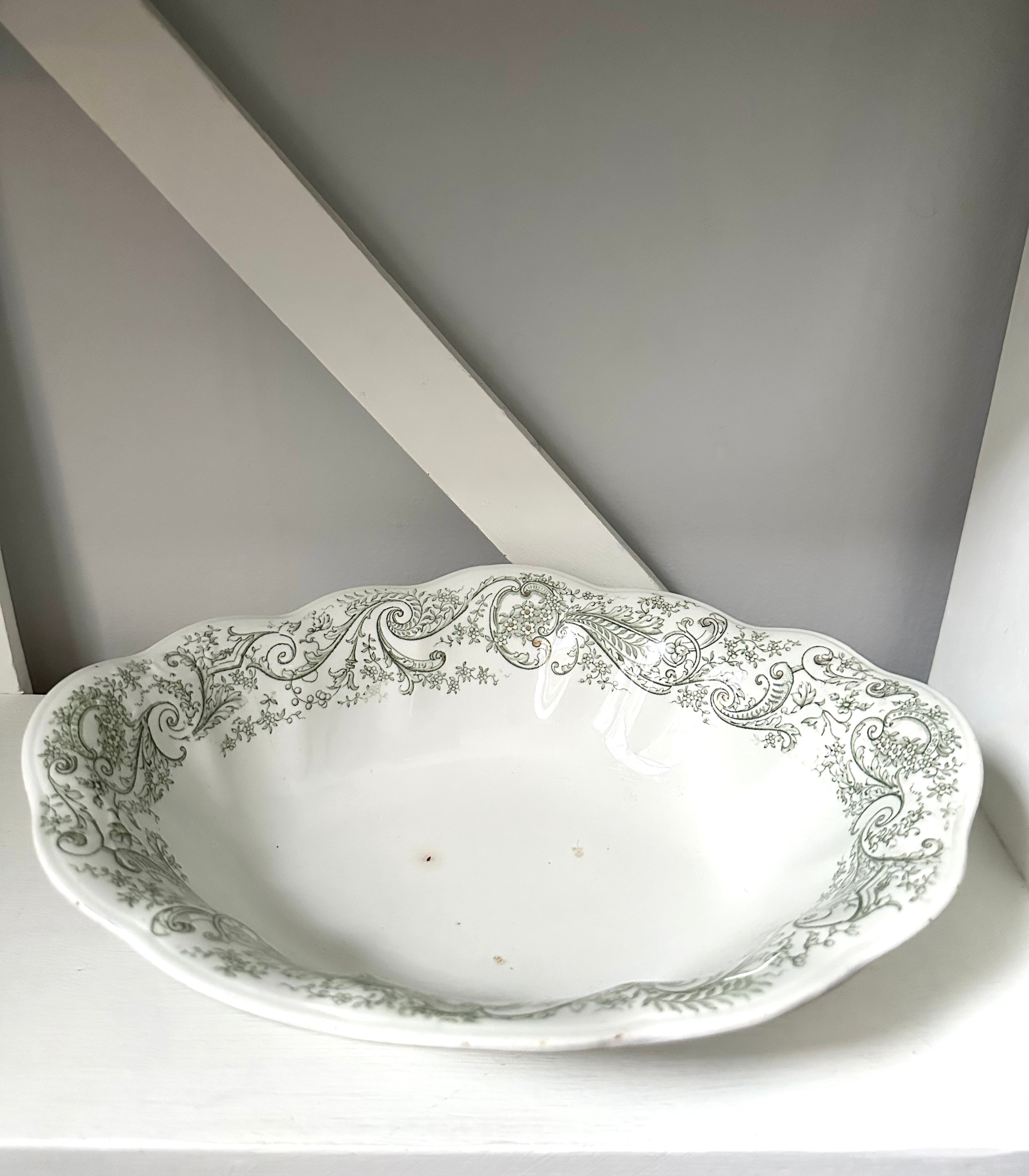 Decorative white ceramic bowl with intricate green patterns on a gray background