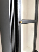 Close-up of a black-framed display unit with a gold fixture on a white background