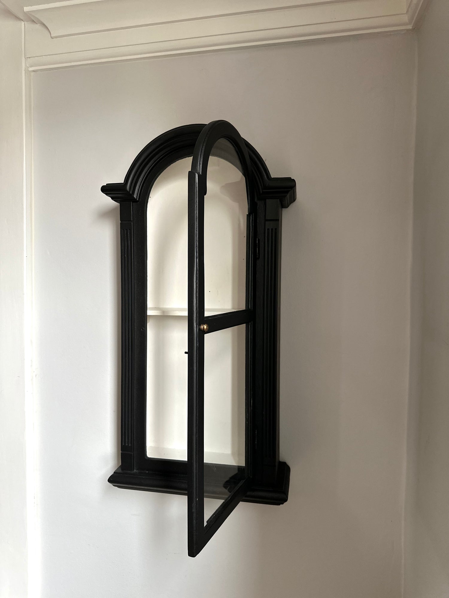Salvaged Old Antique Wall Clock Case turned in to a Black wall-mounted shelf with arched design against a white wall