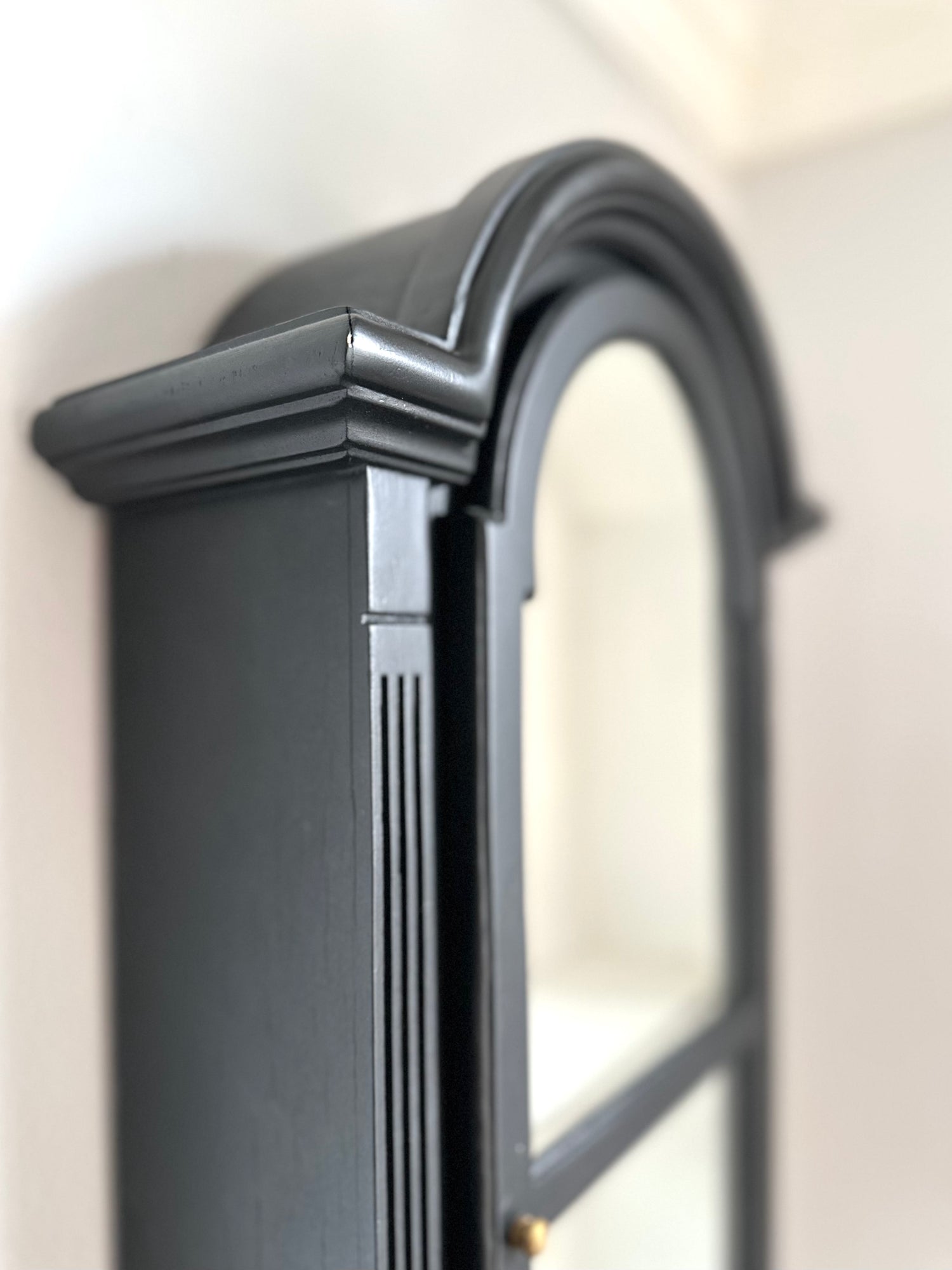 Close-up of a black framed display piece with decorative detailing on a white wall.