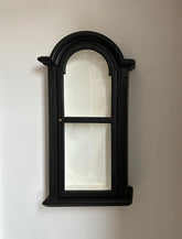 Black framed wall hanging display unit with white interior on a white wall