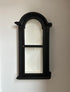 Black framed wall hanging display unit with white interior on a white wall