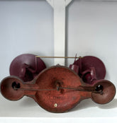 An antique balance scale made in Hamilton is displayed on a white shelf. The cast iron piece features dual weighing pans and a protective cover, showcasing a weathered patina.