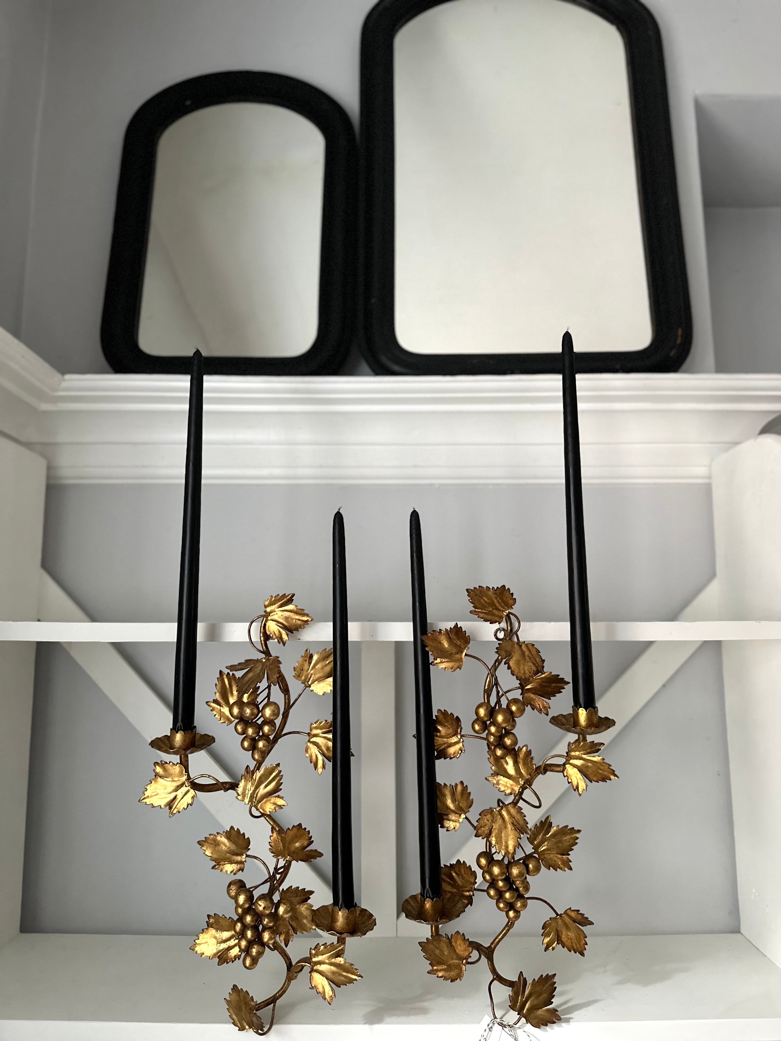 Decorative wall sconces with gold leaf design on a white shelf.