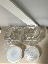 Two glass vintage jars on a linen book with neutral background