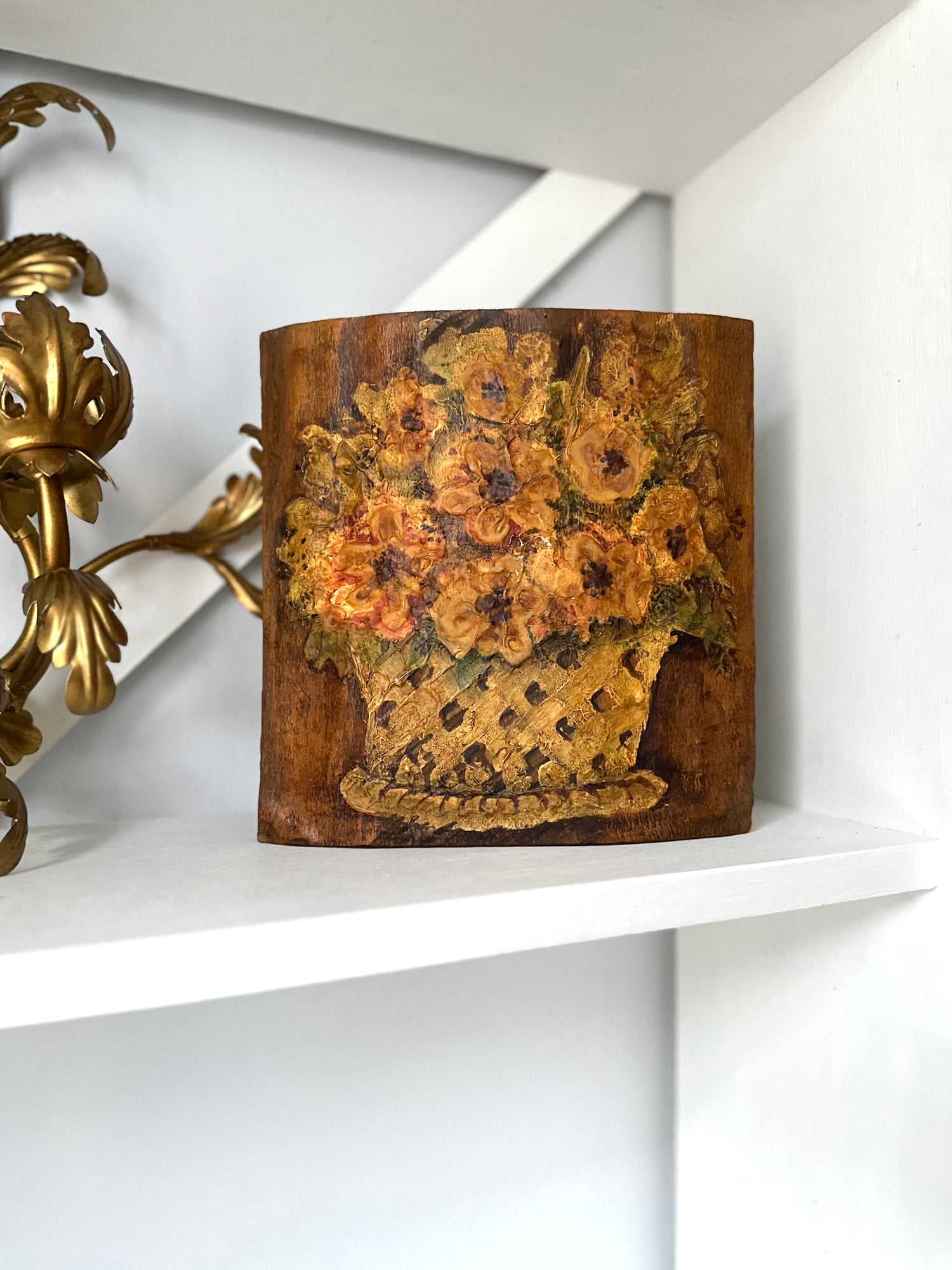 Decorative wooden art with floral design on a white shelf
