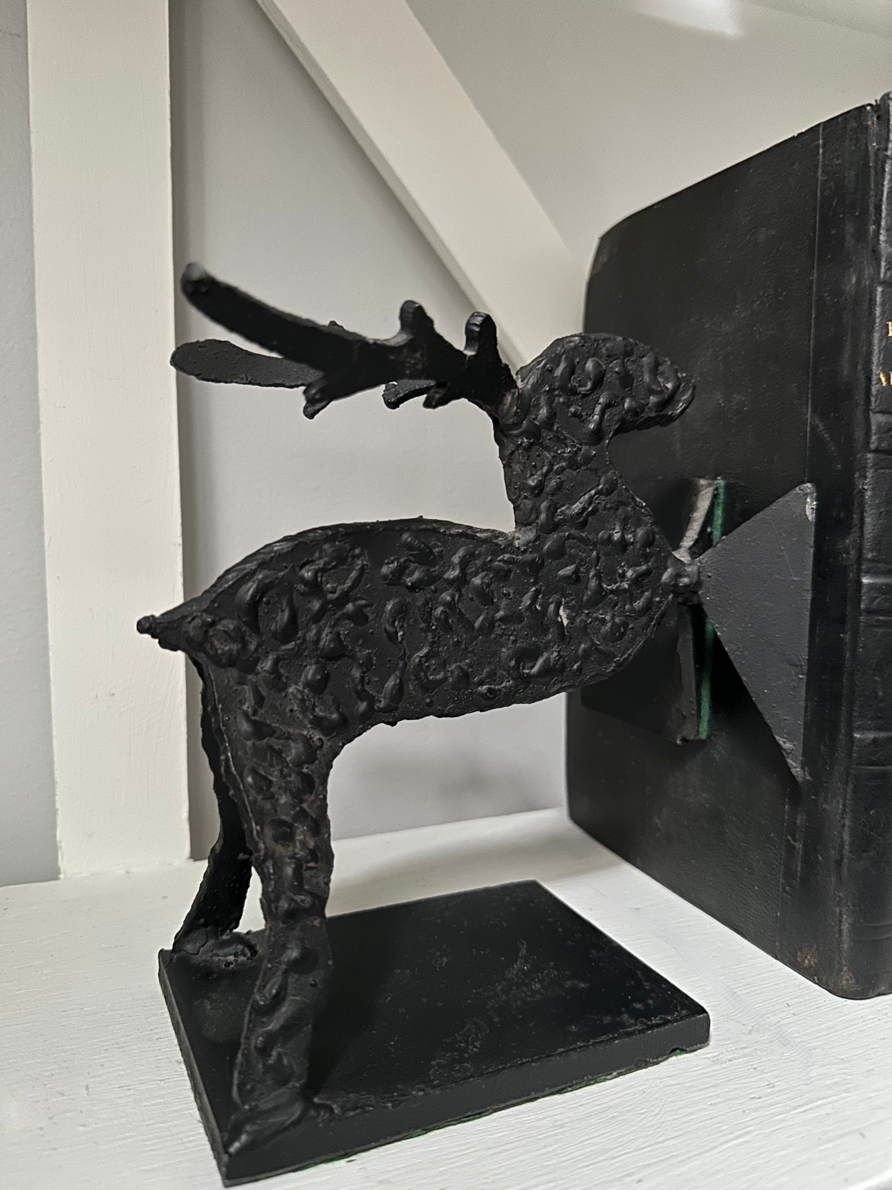 Black cast iron deer bookend on a white surface