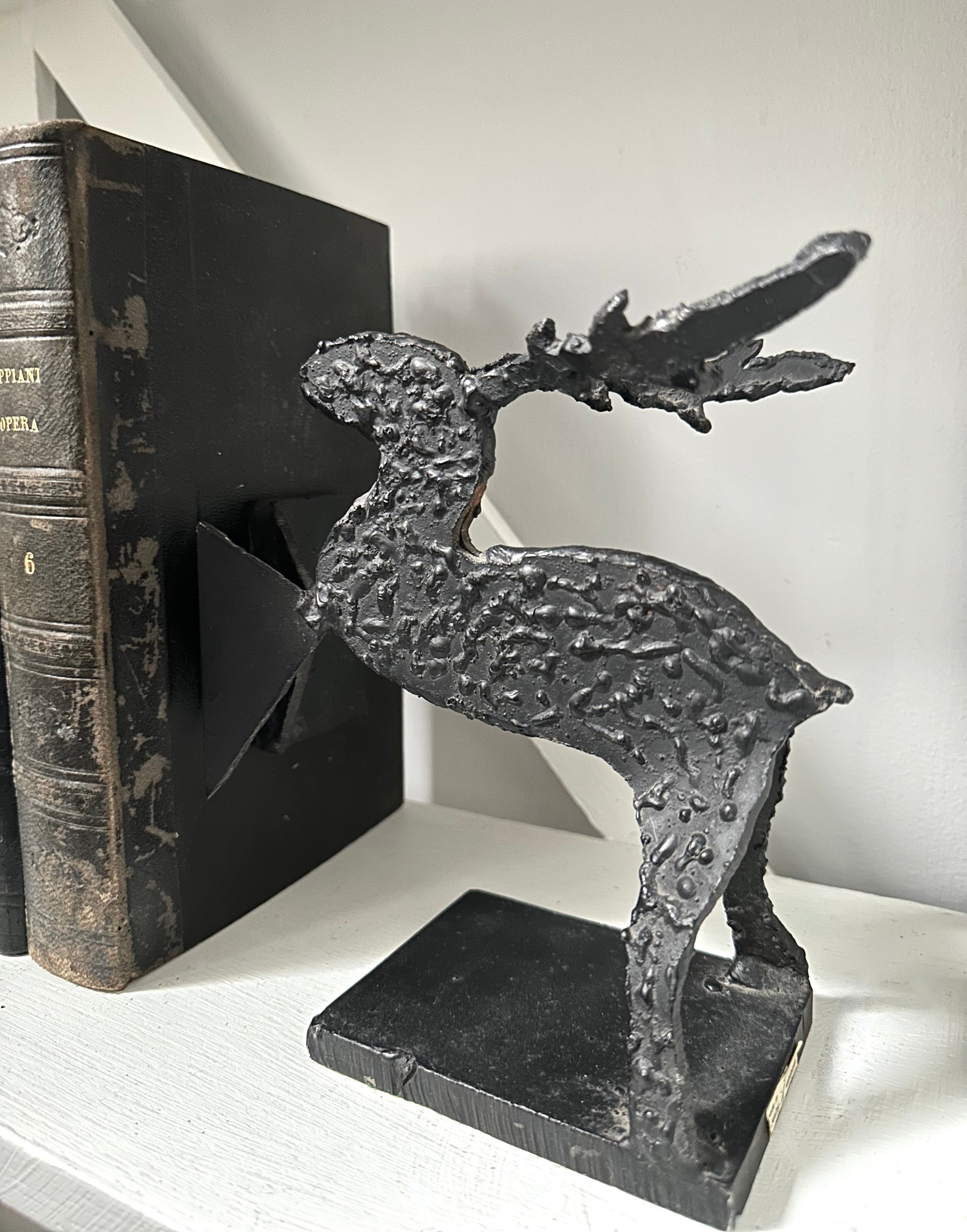 Decorative black metal deer bookend on a white surface with a book in the background.
