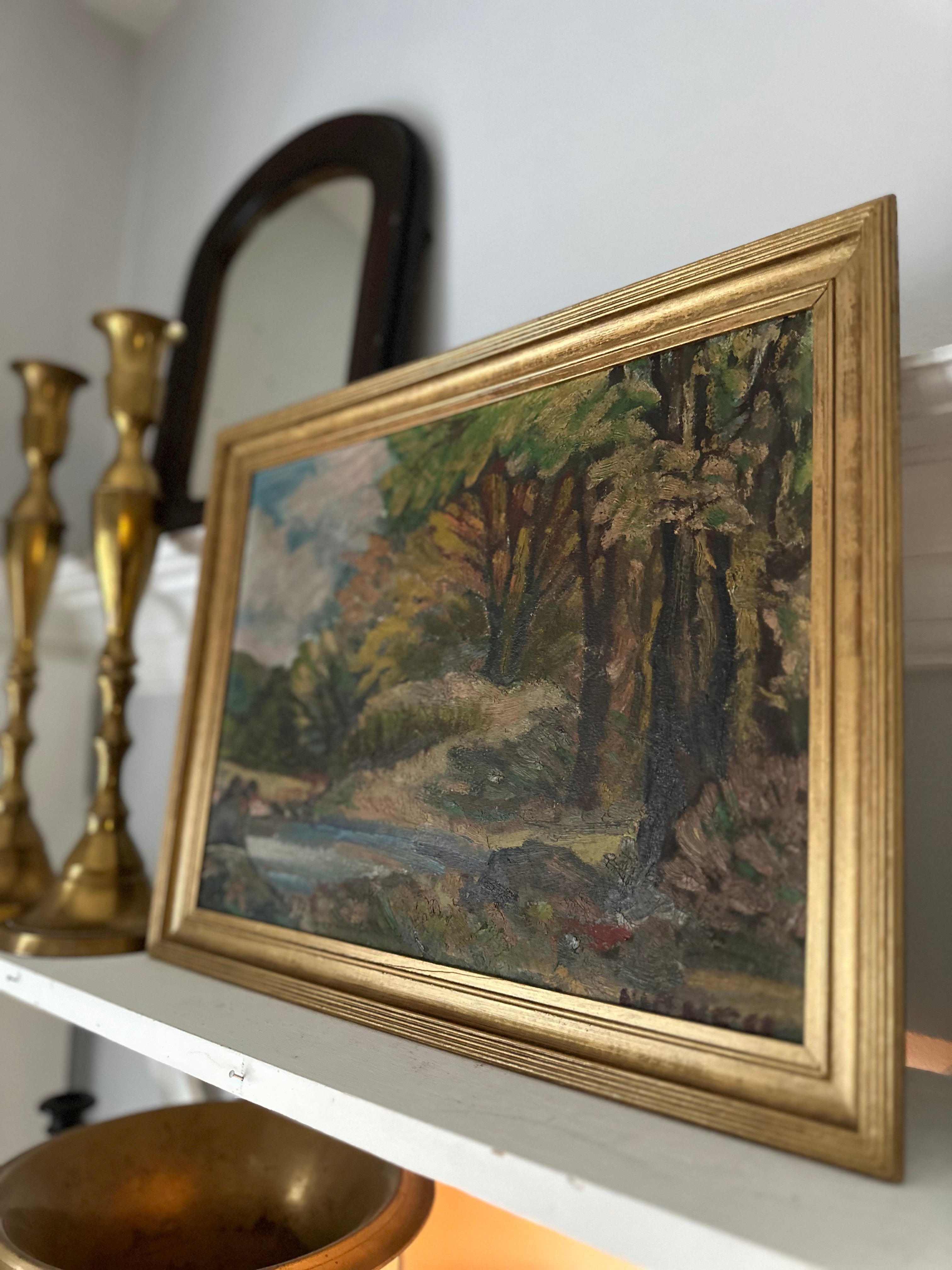 Framed landscape painting on a shelf with decorative items.