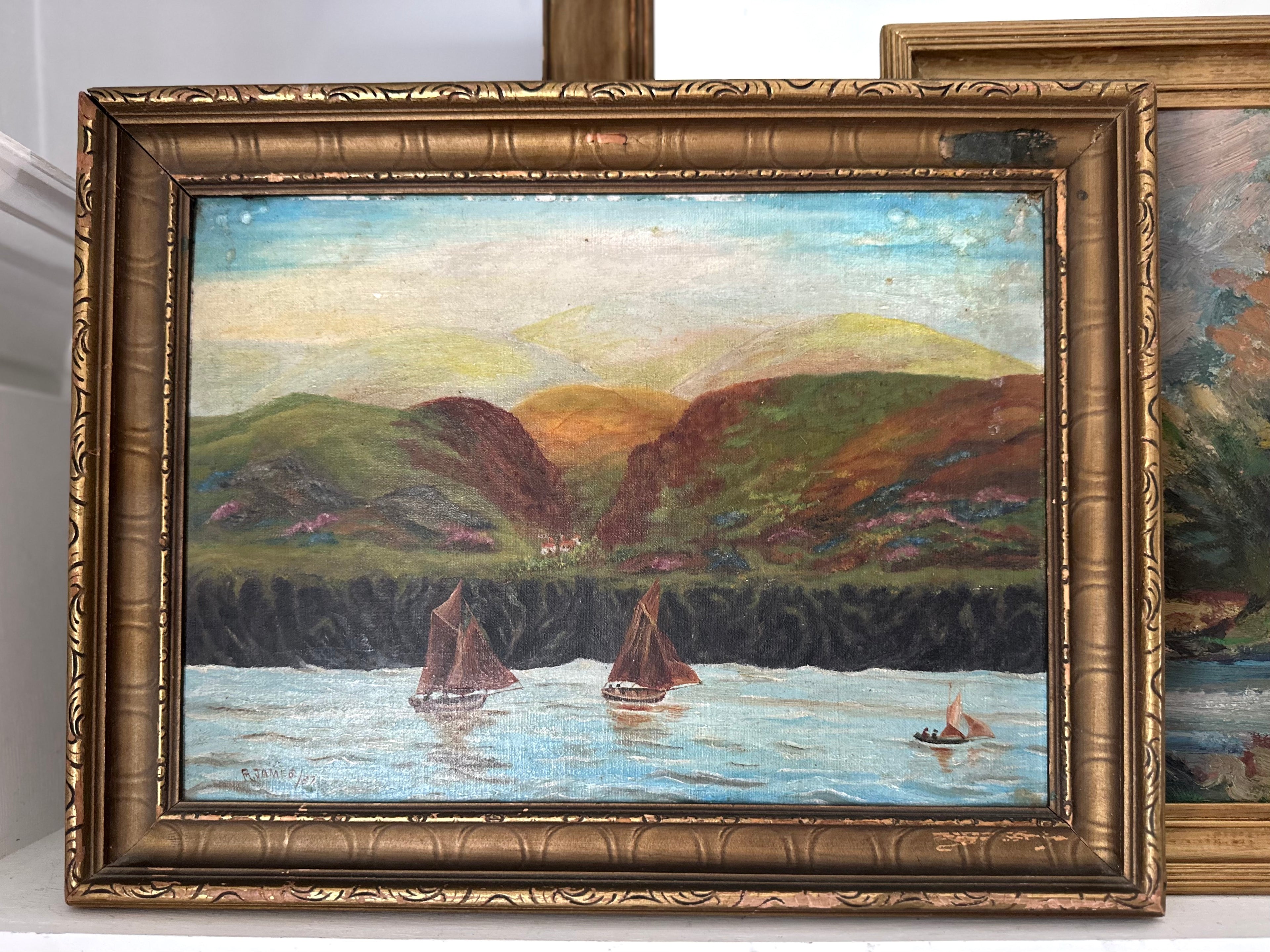An oil painting of a coastal landscape with sailboats on the water, set in an ornate gold frame. The painting features green and brown hills under a pale sky, with the frame partially overlapping another similar painting on the right.