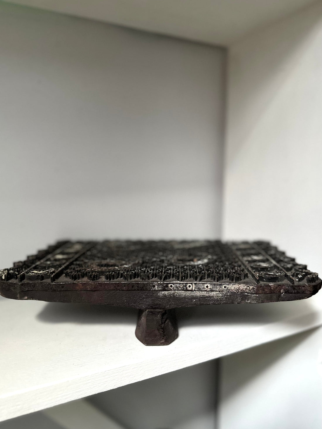 Dark metal object on a white surface with a neutral background