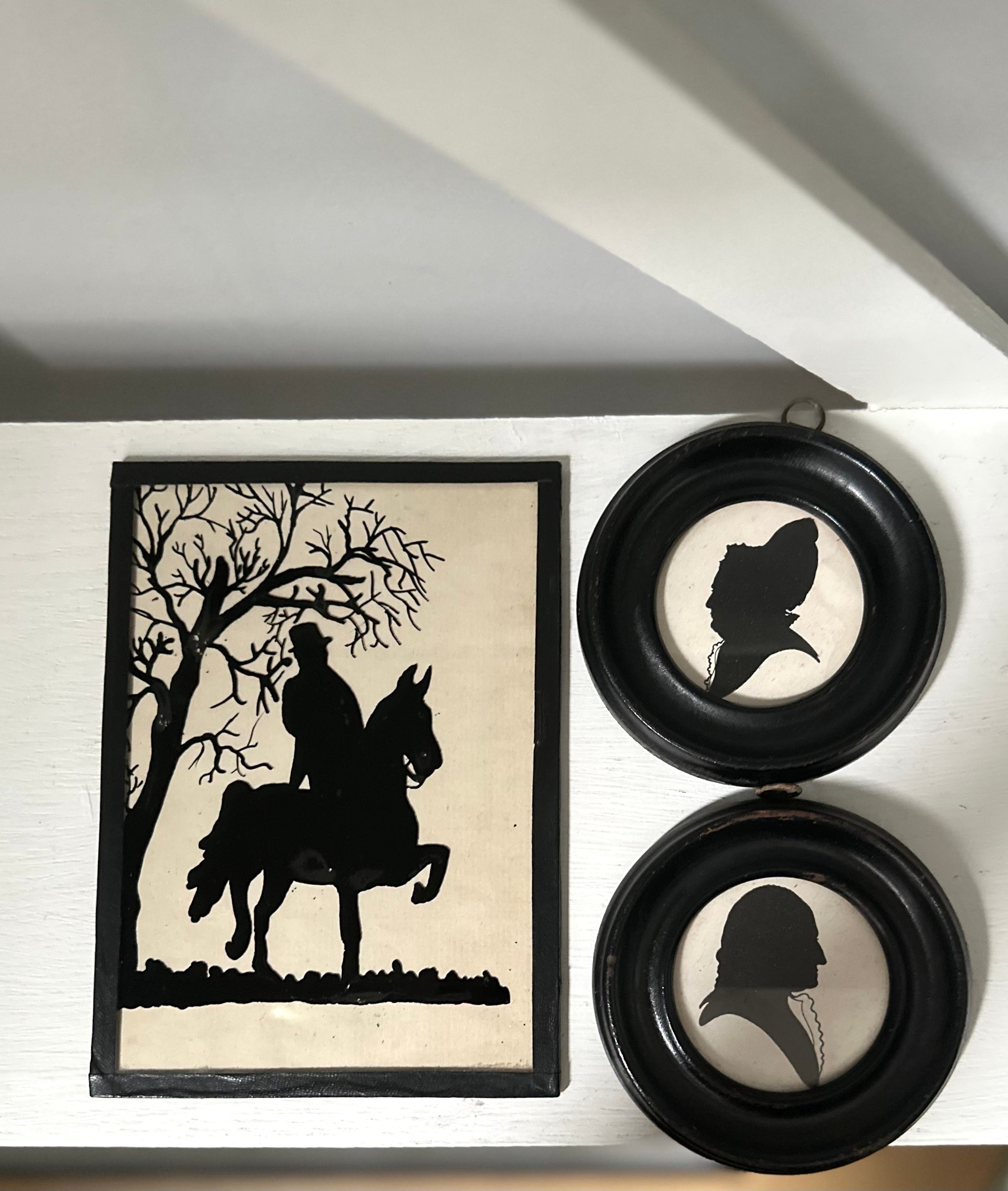 Framed silhouette art of a person on horseback and two circular silhouette portraits.