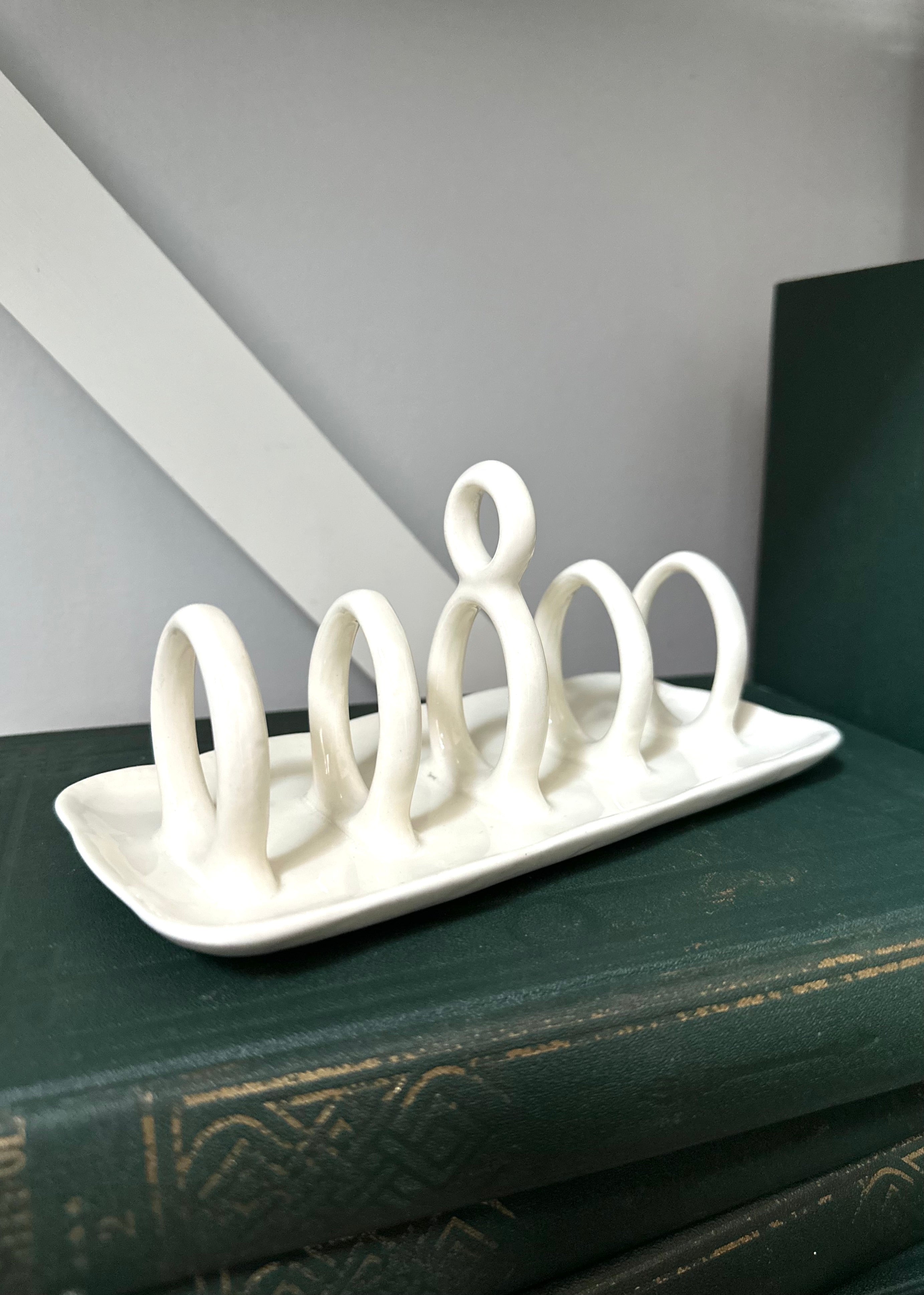 White ceramic plate holder with six loops on a dark surface