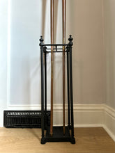 Black coat stand against a white wall with a radiator below