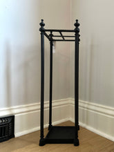 Black coat stand against a white wall