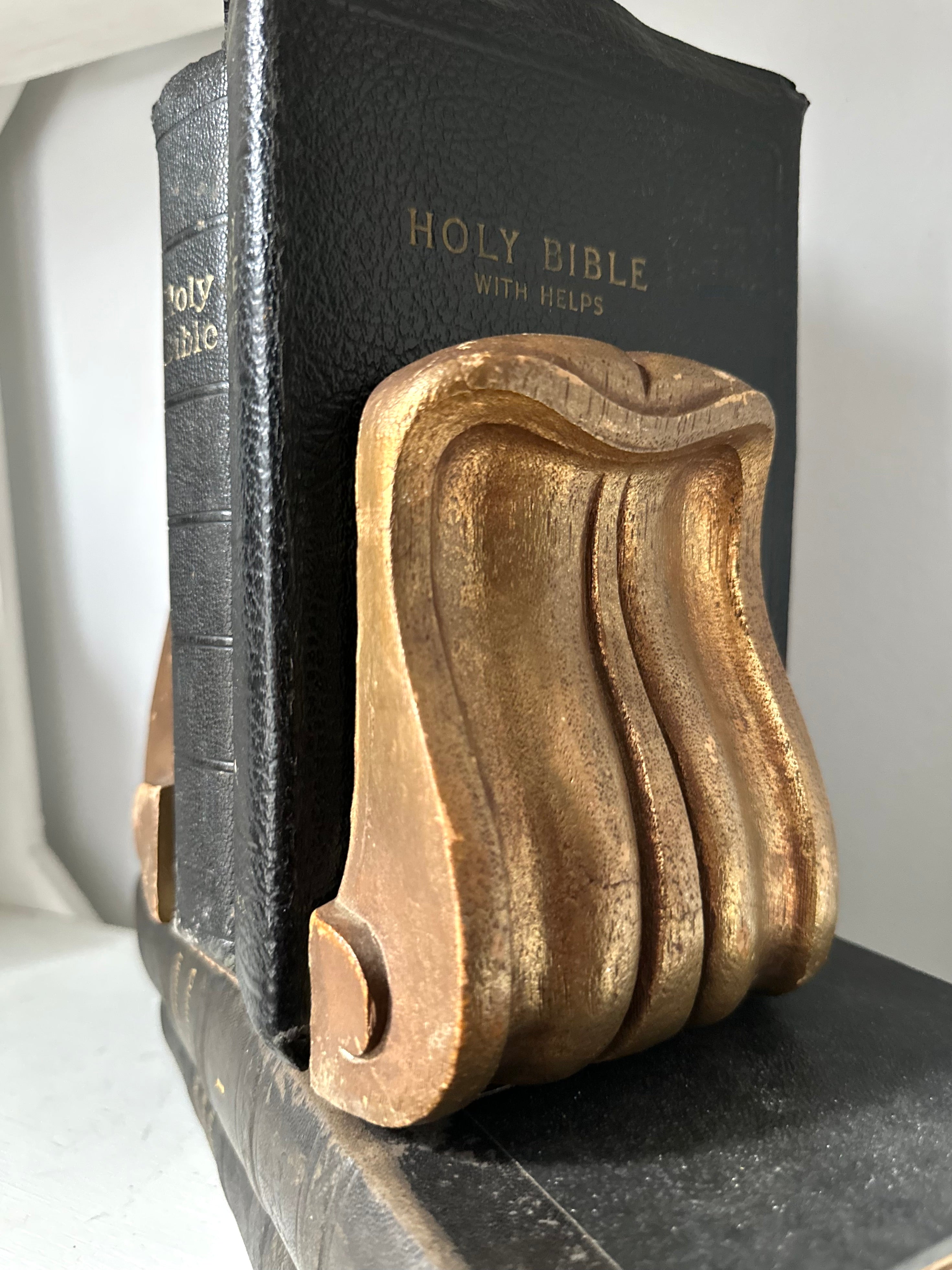 Wooden bookend holding a black Bible on a marble surface