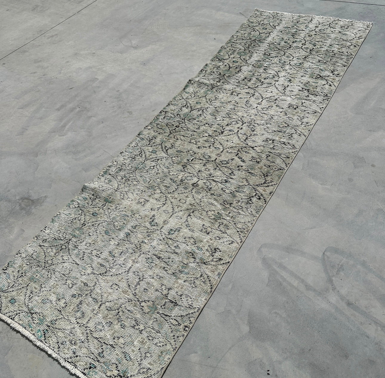 Long rectangular rug with a textured pattern on a concrete floor