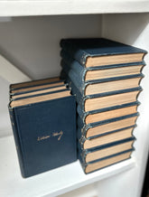 Stack of vintage leather-bound books on a white shelf