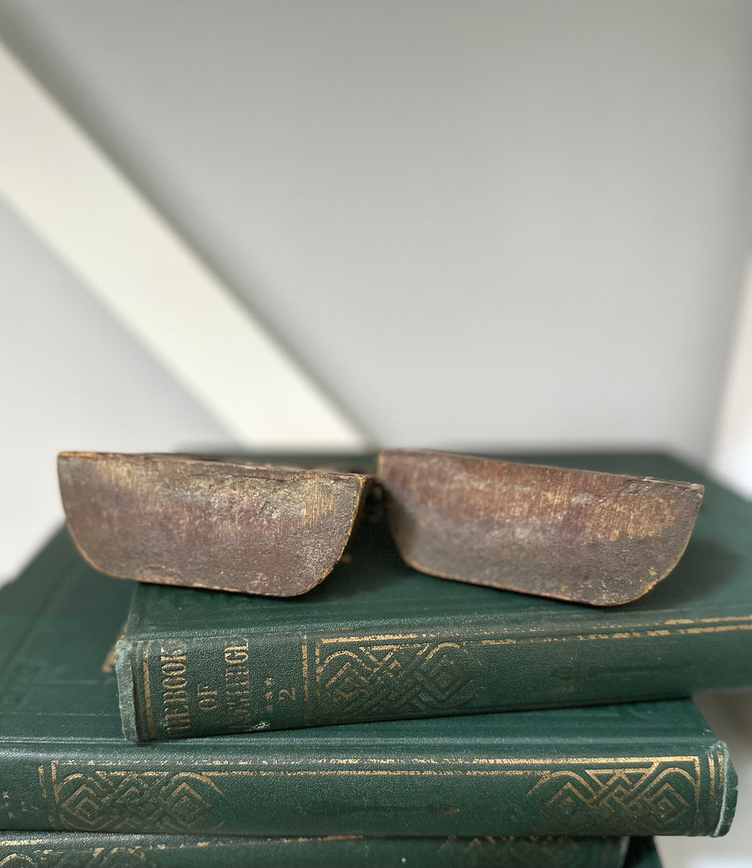 Two antique books with worn leather bindings on a white surface