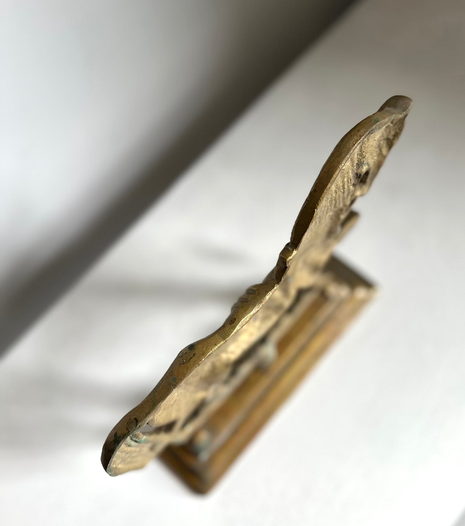 A small decorative brass or bronze figurine of a horse, shown standing on a white surface with a soft shadow.