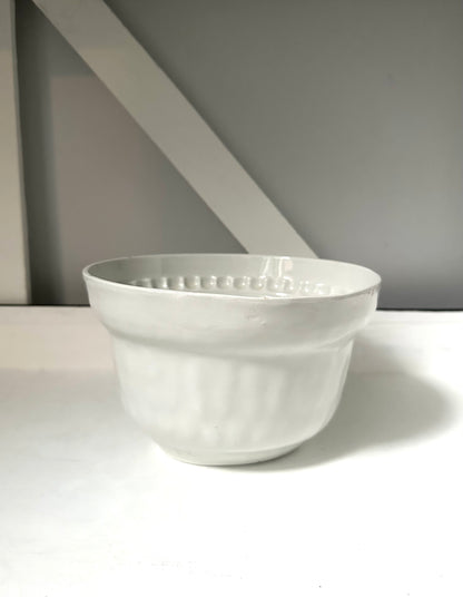 White ceramic bowl on a white surface with a gray background