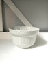 White ceramic bowl on a white surface with a gray background