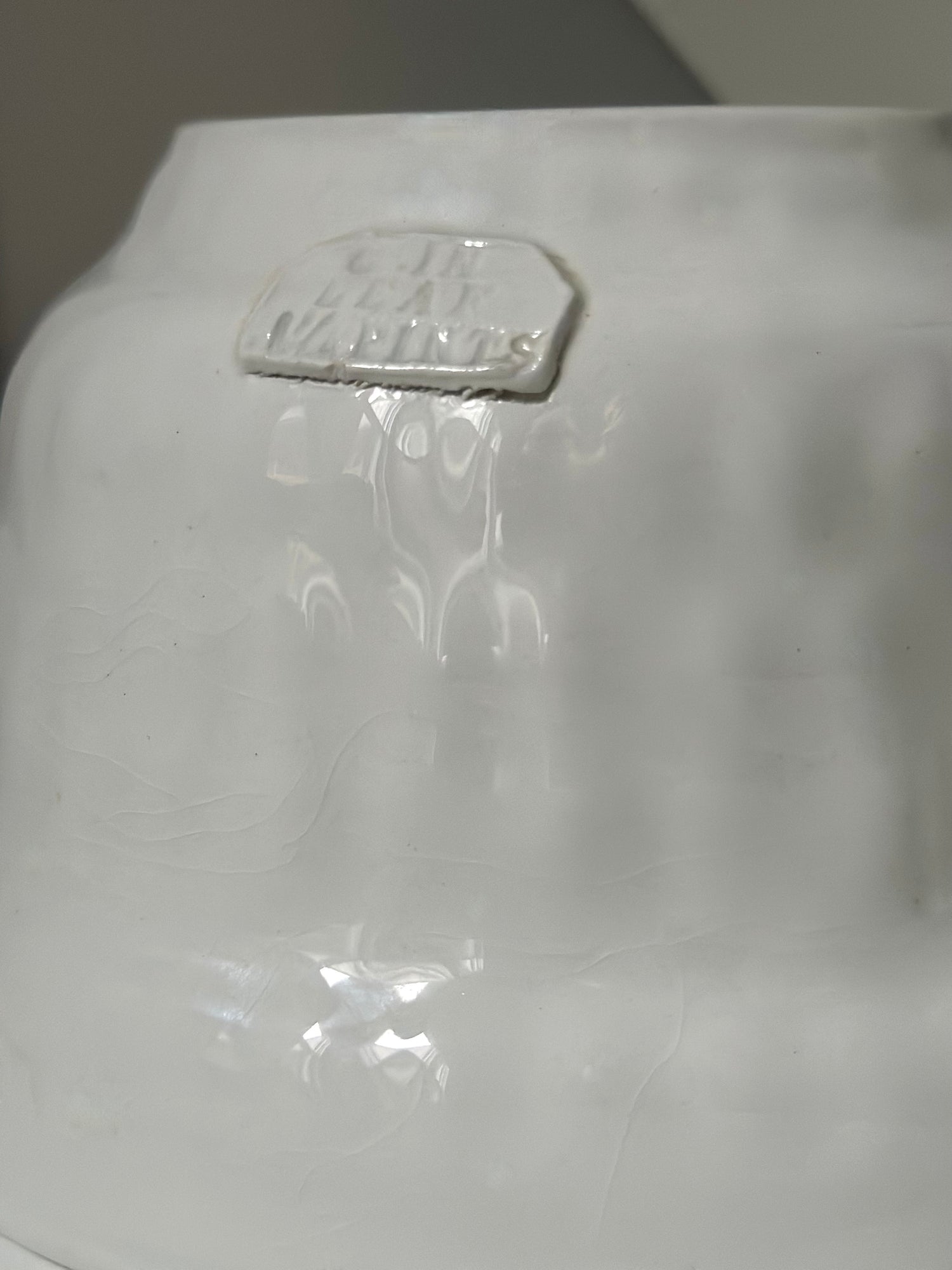 White ceramic vase with a visible brand label on a gray background