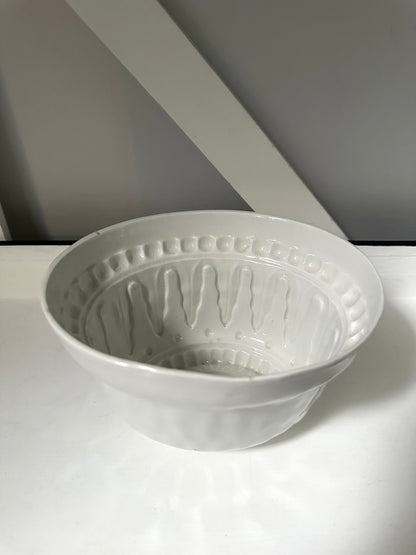 White ceramic bowl with textured design on a white surface