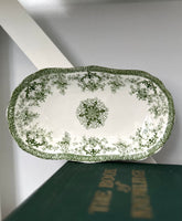 Decorative green and white platter on a book with a plain background
