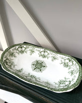Decorative ceramic platter with green floral patterns on a white surface