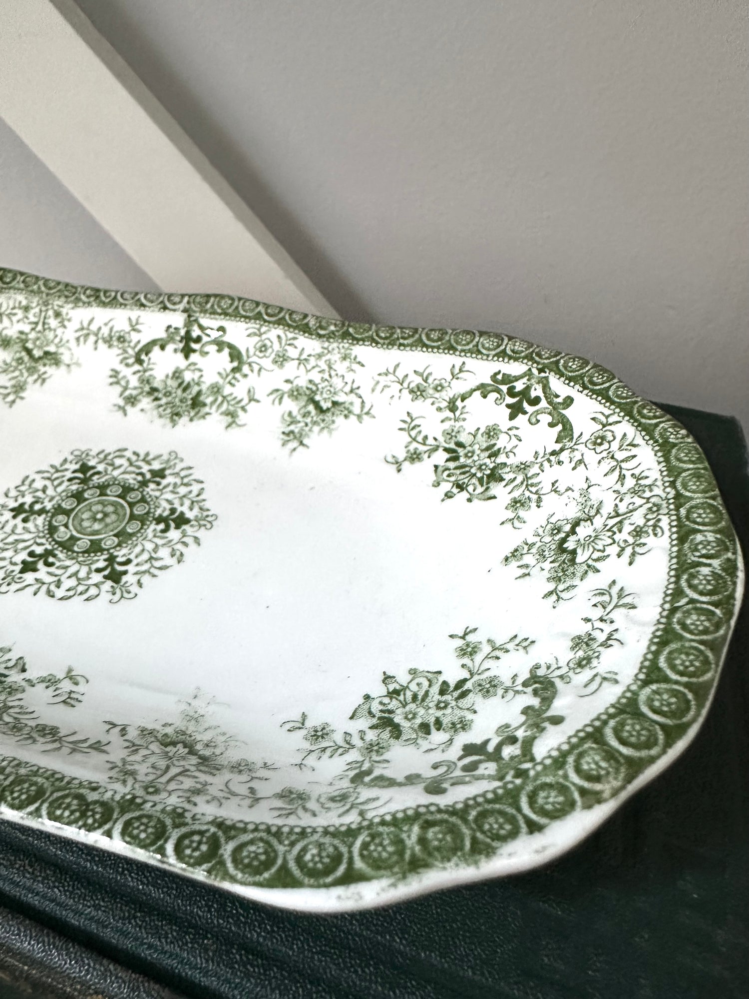 Decorative green and white plate with intricate patterns on a dark surface.