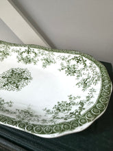 Decorative green and white plate with intricate patterns on a dark surface.