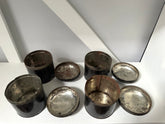 Set of metallic cups and saucers on a white surface with a light gray background