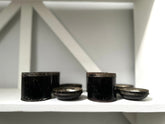 Black cylindrical objects on a white shelf with a white wall background