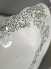 Decorative white dish with green floral patterns on a plain background