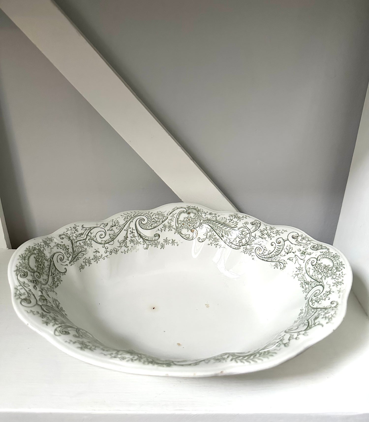 Decorative white ceramic bowl with intricate green patterns on a gray background