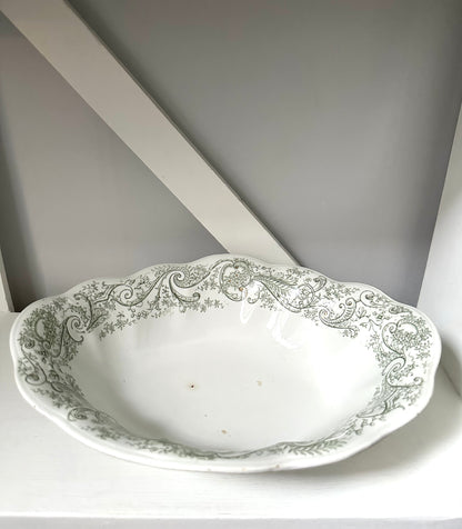 Decorative white ceramic bowl with intricate green patterns on a gray background