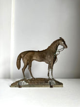 A small bronze sculpture of a horse standing on a rectangular base, photographed against a plain light gray background.