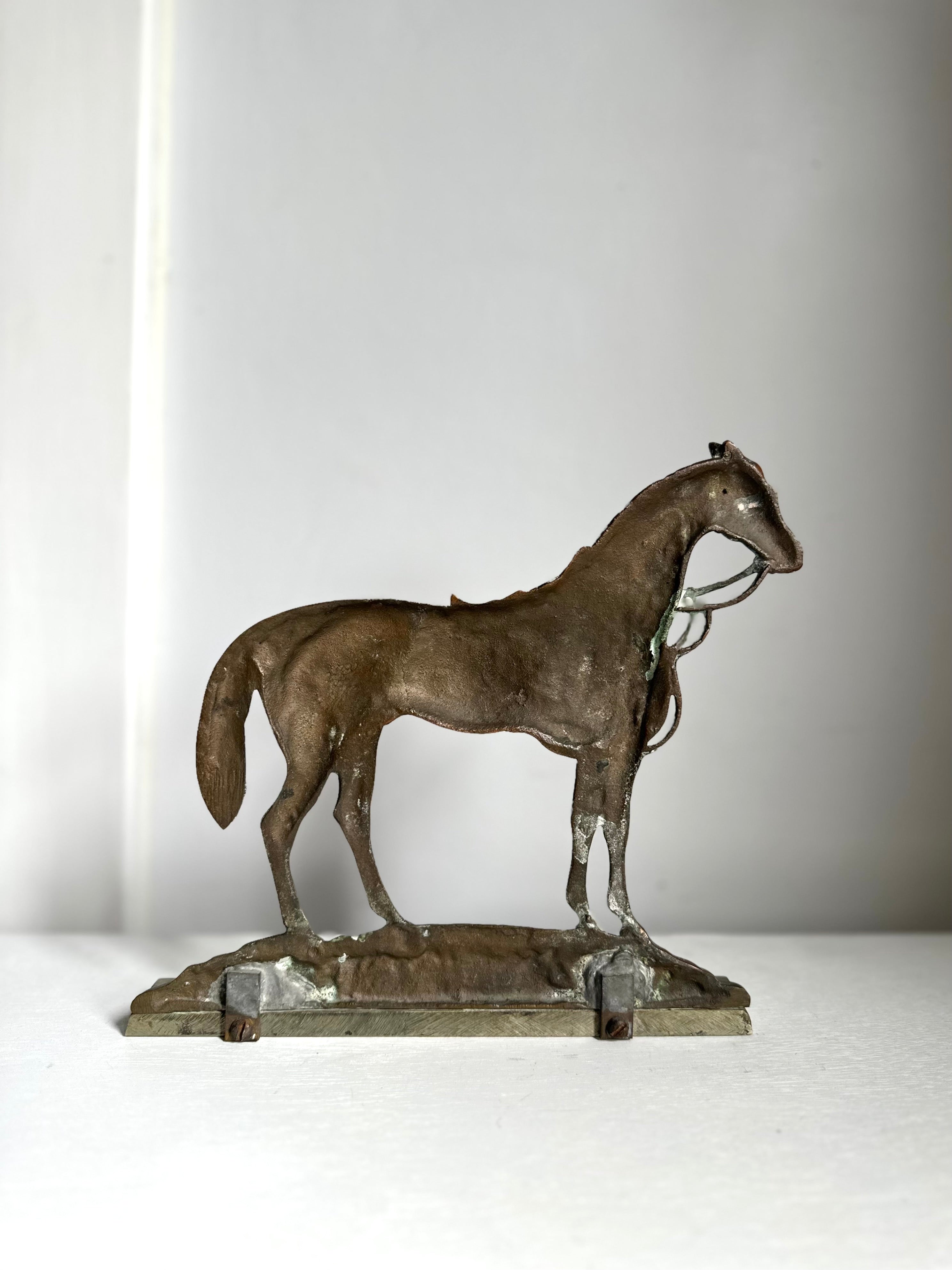A small bronze sculpture of a horse standing on a rectangular base, photographed against a plain light gray background.