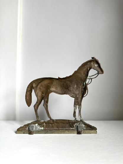 A small bronze sculpture of a horse standing on a rectangular base, photographed against a plain light gray background.