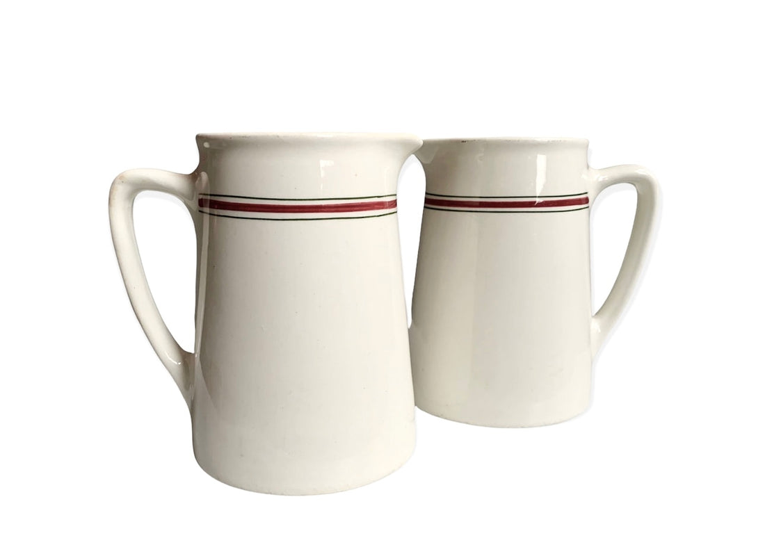 The Pair English Stripe Pitchers evoke vintage style with large handles, a crisp white background, and red and green stripes near the top, reminiscent of classic Hercules pottery.