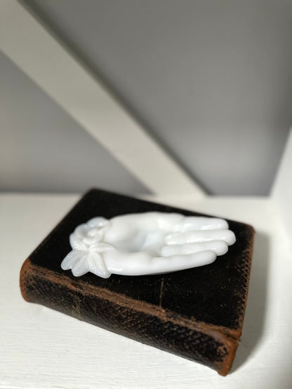 White angel wing figurine on a brown velvet box against a gray background