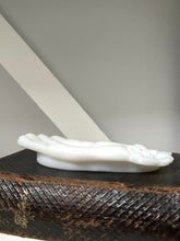 White decorative object on a textured surface with a neutral background