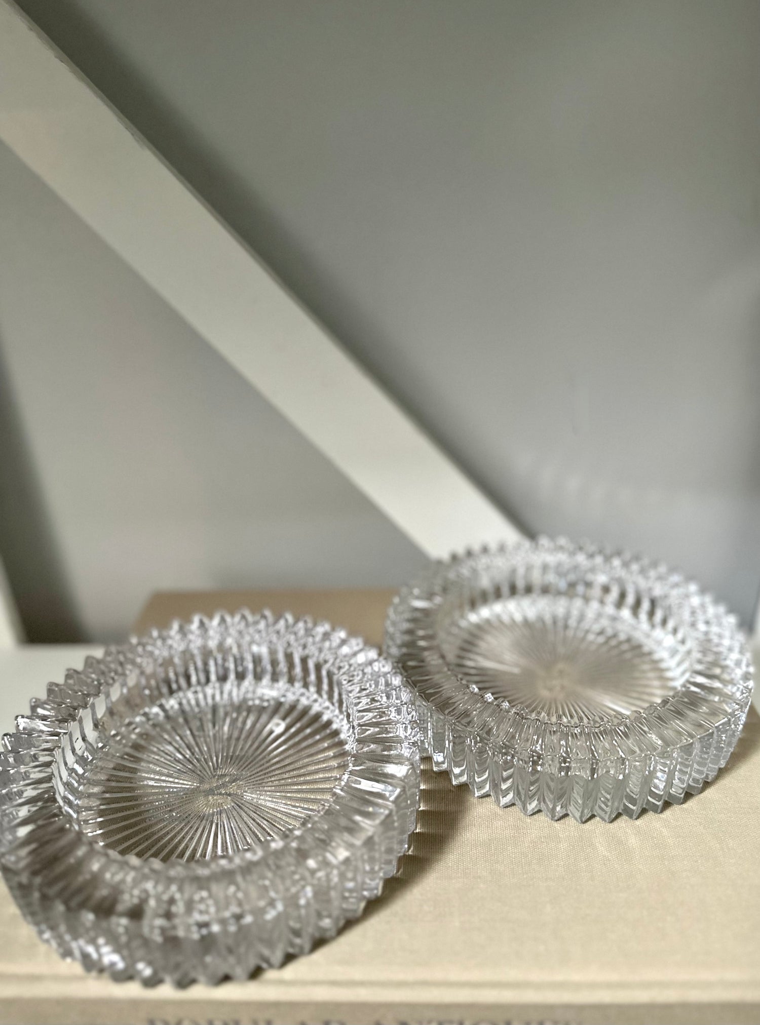 Two glass round ashtray objects sitting on a book with a light background