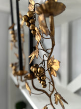 Decorative metal vine with gold leaves and berries on a white background