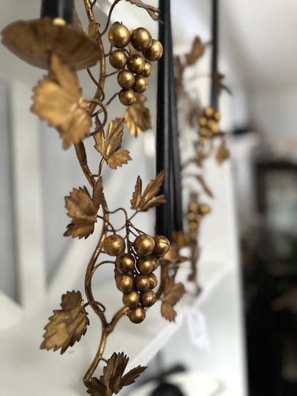 Decorative metal wall art with gold leaves and grapes on a white background