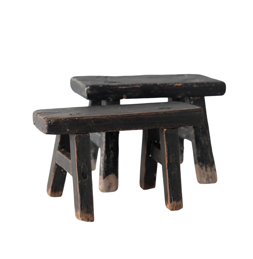 Two wooden stools with a worn black finish on a white background